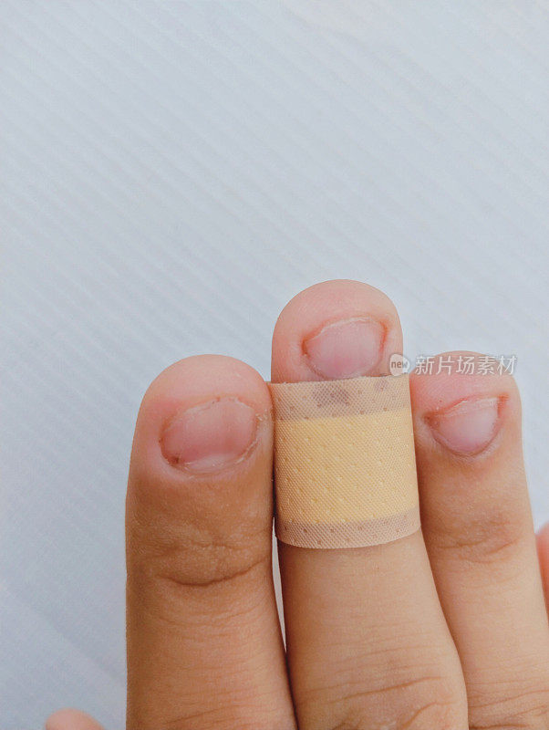 人体割伤手指上的胶布贴在轻微割伤手指上的膏药医用急救胶带近景图像照片