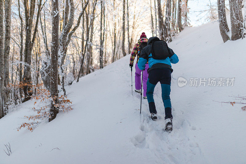 两个年轻的徒步旅行者在冬天爬上雪山