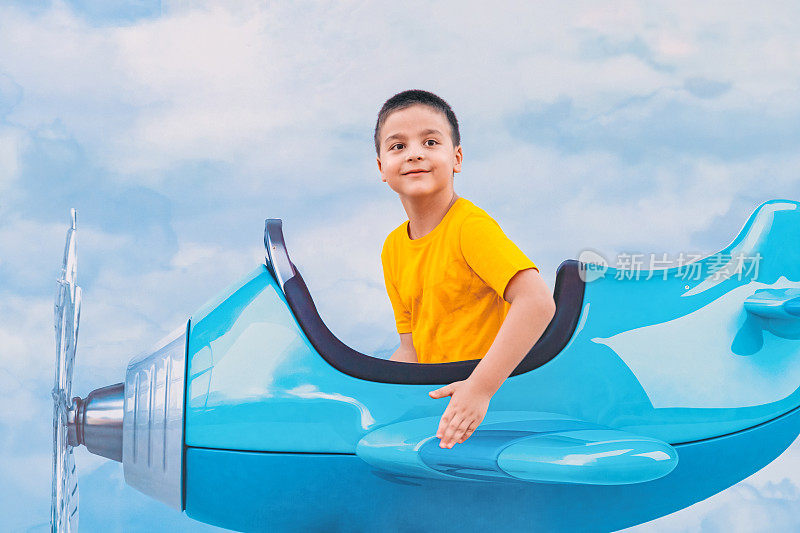 小男孩坐在玩具飞机里在天空中飞翔