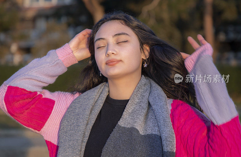 年轻的亚洲女子享受阳光打她的脸