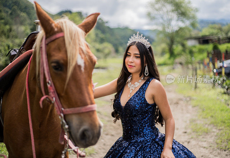 青少年妇女的肖像quinceañera连衣裙和自然背景上的马头饰