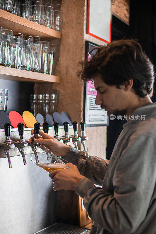 一个年轻人正在啤酒酒吧里倒啤酒。