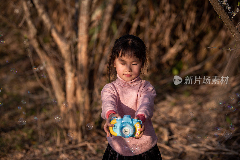 一个亚洲女孩在梅园里玩泡泡玩具