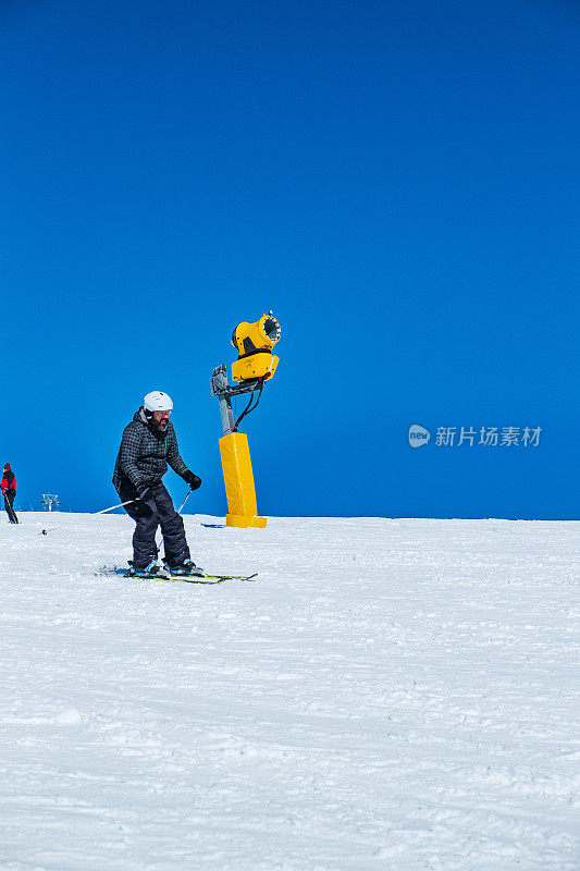 滑雪者沿着积雪覆盖的斜坡慢慢地滑下，滑雪度假