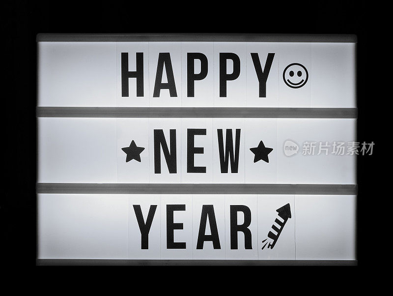 黑色背景上有一个写着“新年快乐”字样的灯箱。