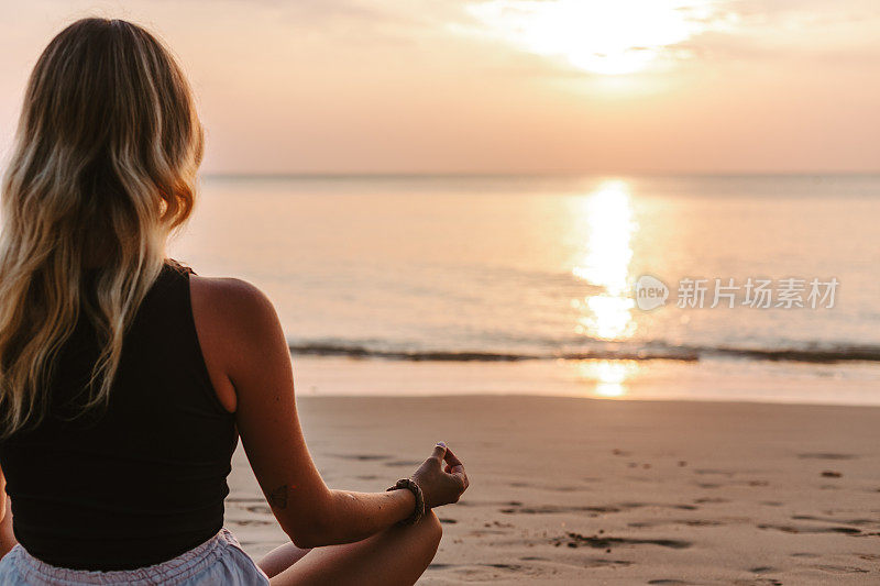 年轻女子在海滩上练习瑜伽