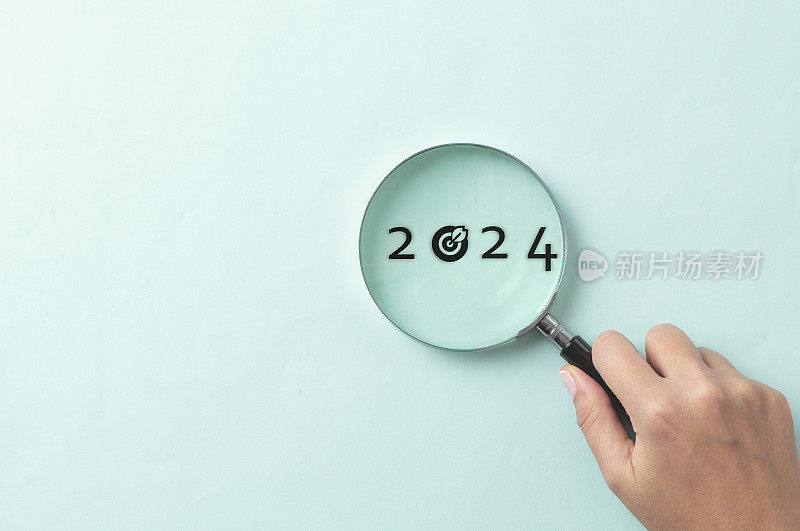 2024年放大镜内2023年和2024年之间的焦点和集中新的业务年，圣诞快乐和新年快乐的概念