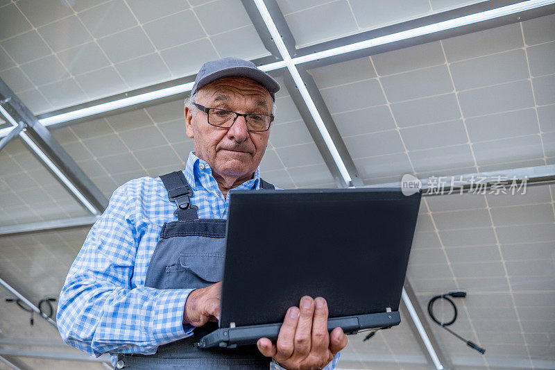 一名技术人员将笔记本电脑放在太阳能电池板下。