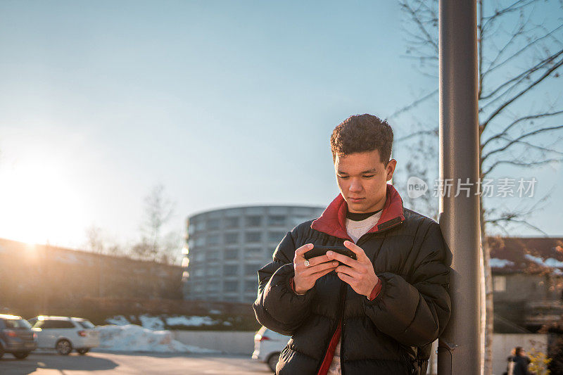 亚洲男性青少年在城市环境中使用智能手机发短信