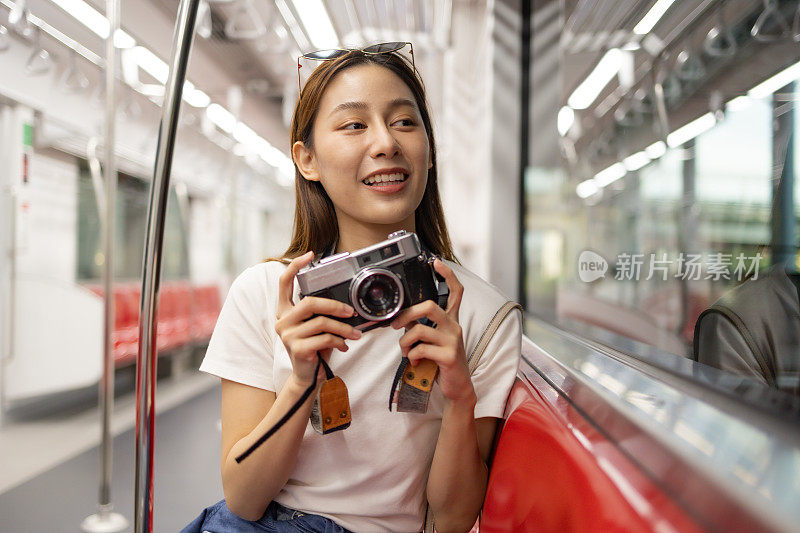 亚洲女游客带着坐着拍照的旅行地点和观光城市的窗外景色，公共火车交通，城市生活方式的铁路之旅