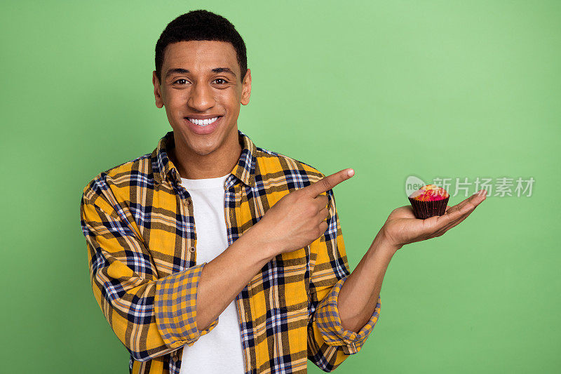 照片中的帅哥正面直接手指手臂拿纸杯蛋糕空空间隔离在绿色的背景