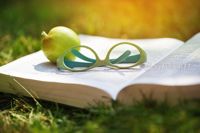 特写镜头的眼镜上的一本书与苹果