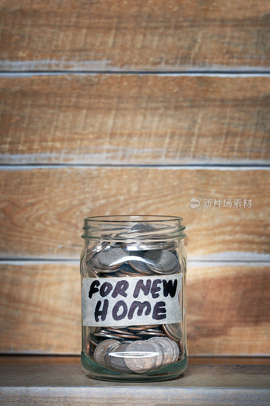 玻璃罐与钱硬币和标签上的题词“新家”在一个白色的背景