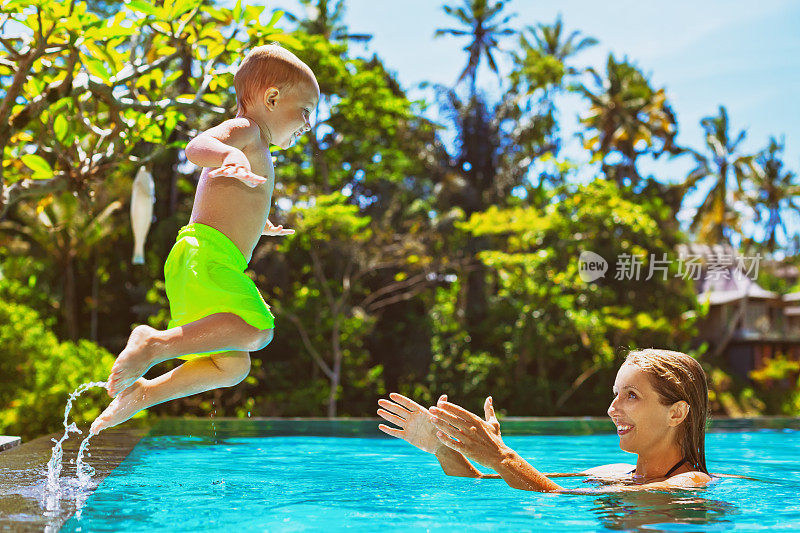 快乐的孩子在游泳池里跳到妈妈手里