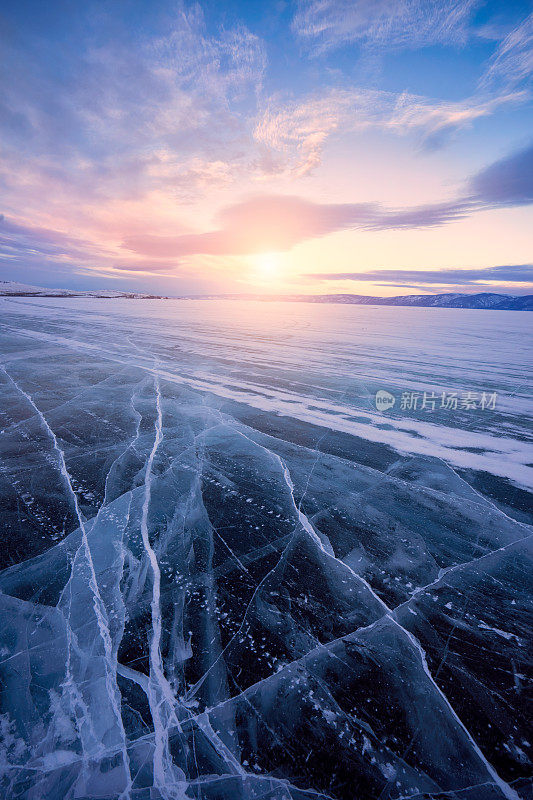 贝加尔湖冬天温暖的日出。冰面上美丽的裂痕。