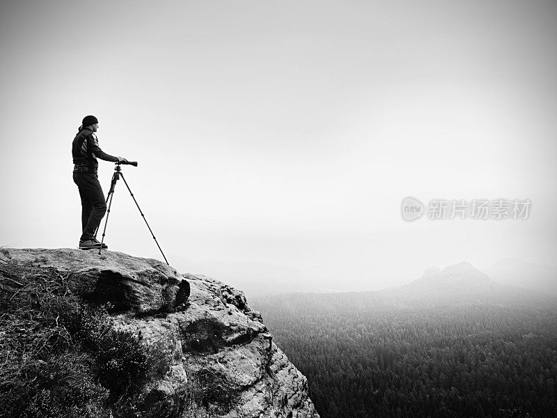自然摄影师准备相机拍摄令人印象深刻的照片，雾蒙蒙的瀑布山。旅游摄影师