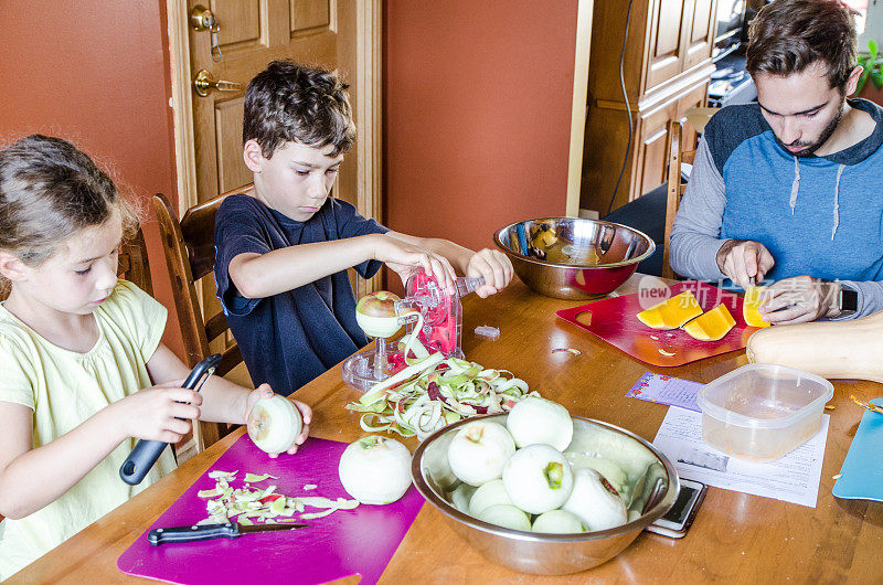 父亲和孩子们在餐桌上削苹果和南瓜皮