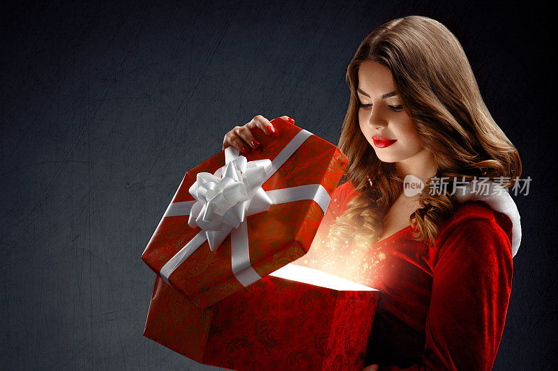 性感的年轻女子穿着红色的圣诞老人与礼物。在达