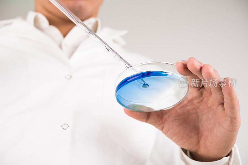 科学家用移液管从培养皿中提取液体