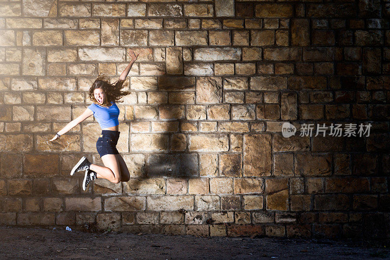 美丽的少女跳的石头墙的喜悦