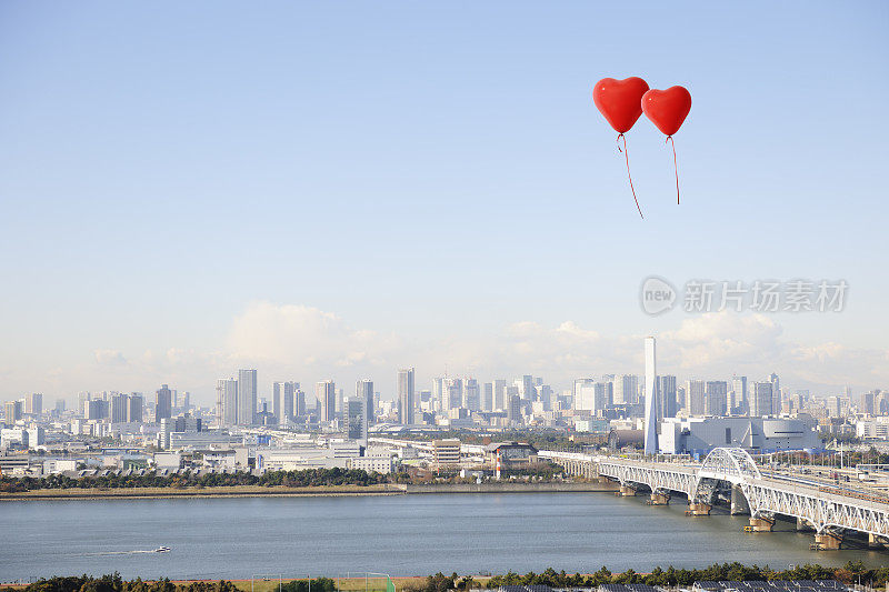 红色的心形气球漂浮在清澈的城市天际线上