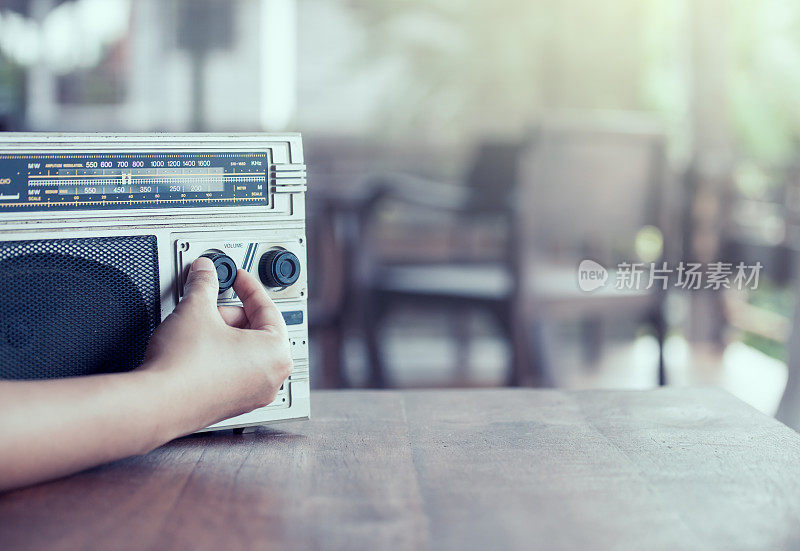 女人用手调整着复古收音机盒式立体声音响的音量