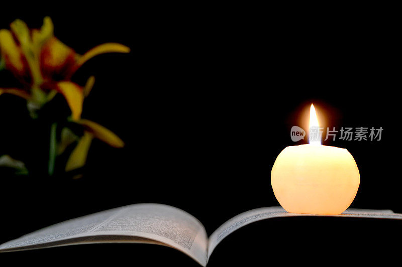 蜡烛，打开的书和花孤立在黑色的背景