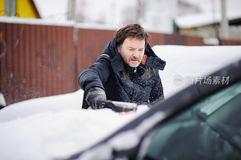 一名男子正在用工具清理车上的积雪
