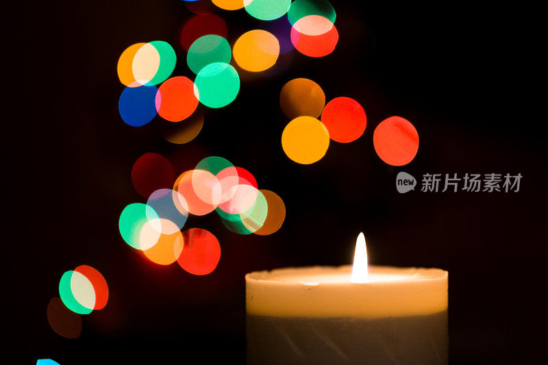 燃烧的蜡烛与缤纷的圣诞散景背景