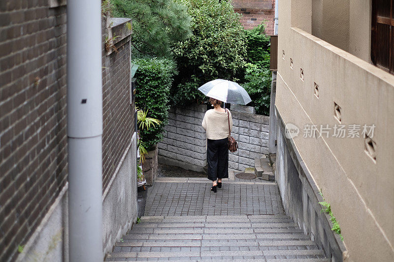 在一个雨天，在东京神乐坂传统老城的小巷里走着的女人的背影