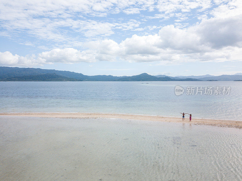 这是一对年轻夫妇在菲律宾群岛热带海滩上放松的无人机鸟瞰图。人们旅行豪华度假目的地的概念