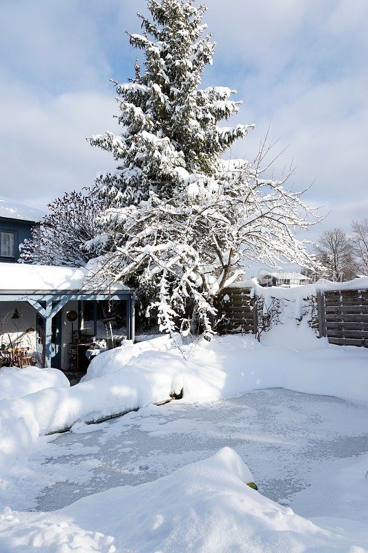 2019年1月暴风雪后的房子、花园和池塘。巴伐利亚,德国。