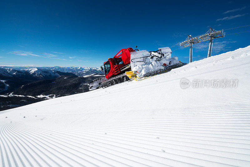 现代的红色雪清理过剩的雪在一个美丽的，阳光明媚的日子在山上滑雪道的下坡