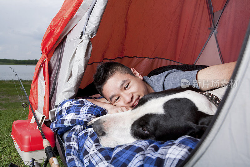 少年躺在帐篷和狗