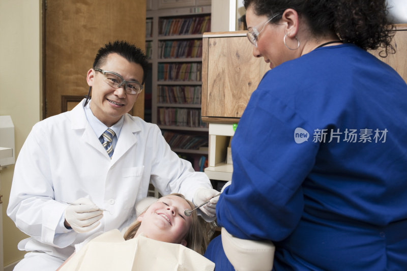 亚洲牙医与卫生员工作的病人，微笑