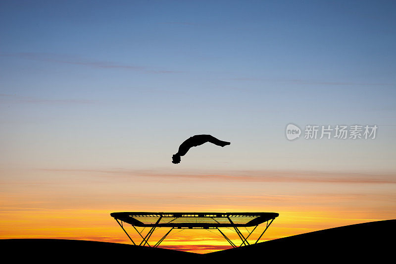 日落时分，体操运动员在蹦床上的剪影