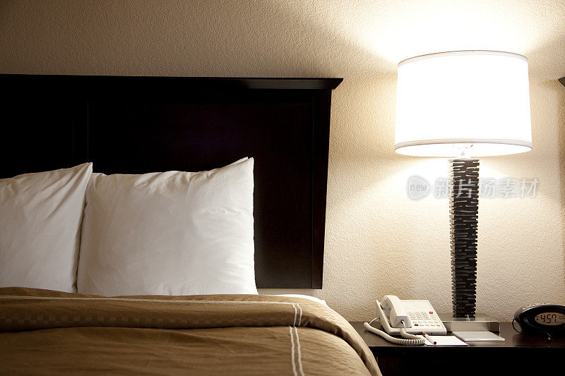 酒店房间的床上有枕头、床头柜和羽绒被。灯。