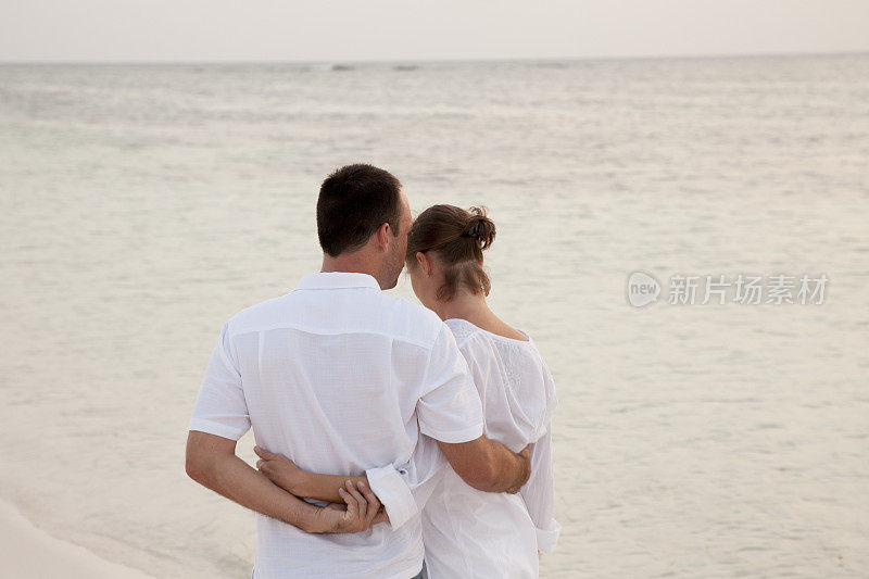 蜜月夫妇拥抱和沿着加勒比海滩海岸线散步