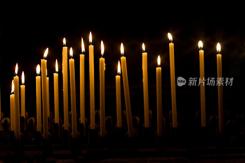 许多点燃的教堂蜡烛在黑色的背景