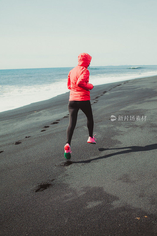 在冰岛黑沙滩上跑步的女人