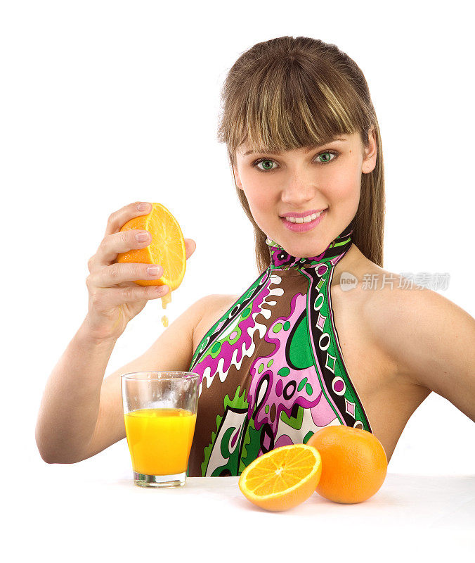 美丽的年轻女子从橘子中挤出果汁。