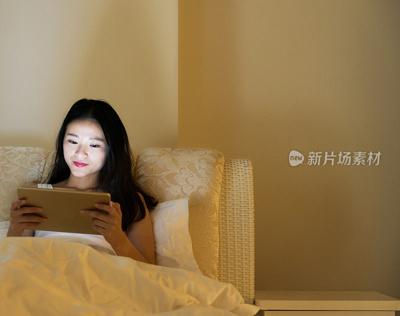 晚上在床上用平板电脑的女人
