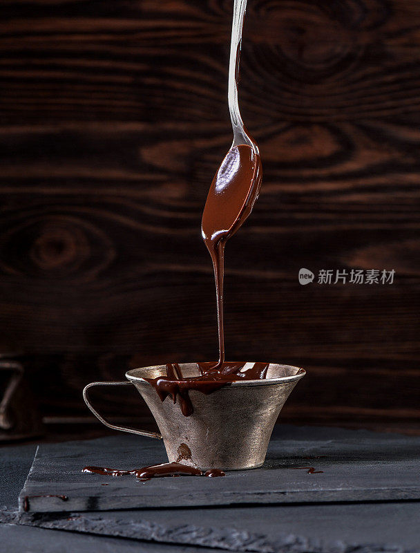液态巧克力从勺子滴到杯子里