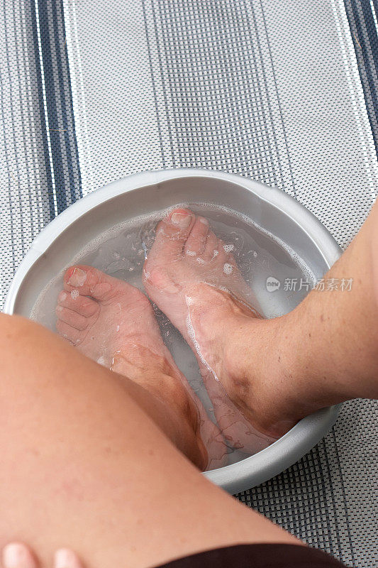 一个人把脚泡在一碗温水里