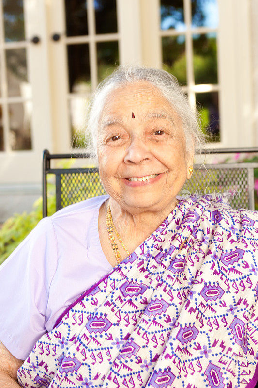 户外肖像的年长印度妇女在紫色纱丽垂直