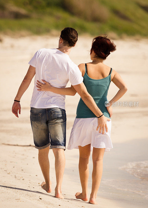 异族情侣在沙滩上散步，抚摸着屁股