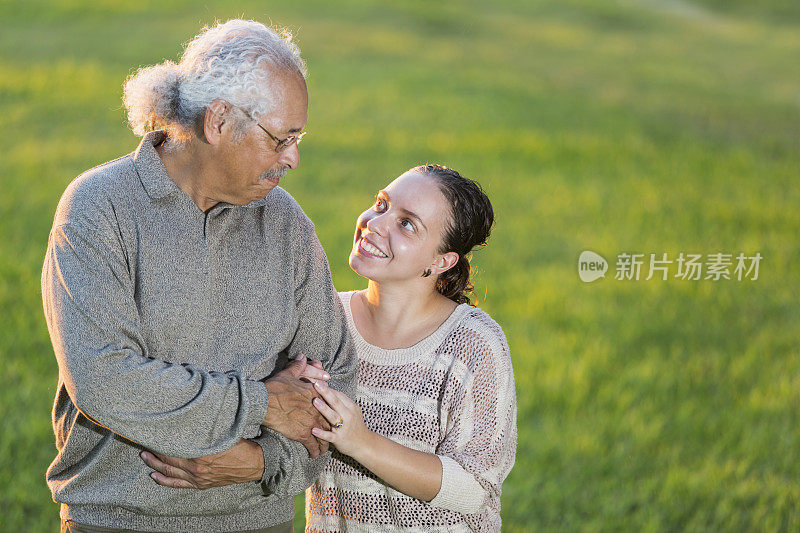 西班牙老人和成年女儿手挽着手站在一起