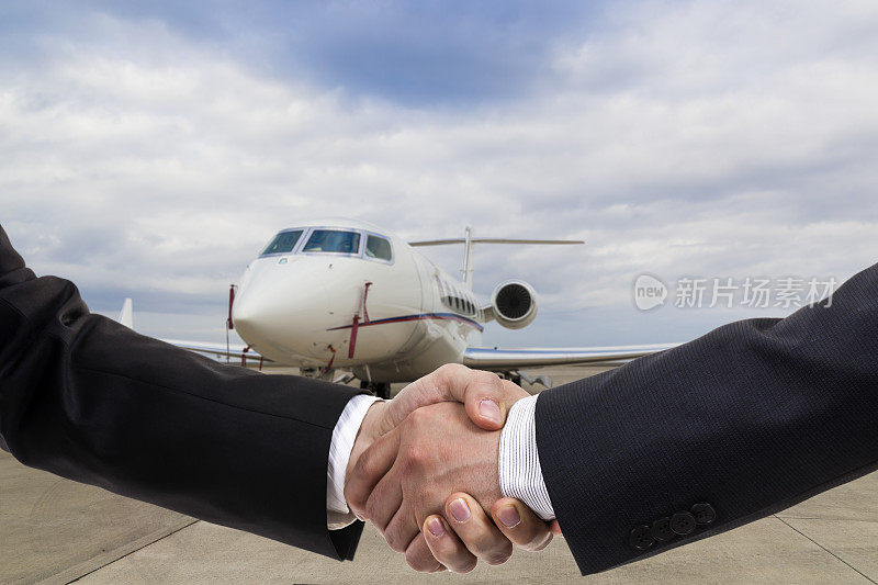 商人们在商务飞机前握手