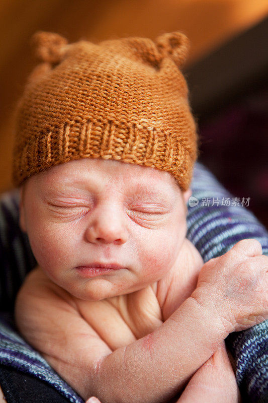 戴着帽子睡着的新生男婴
