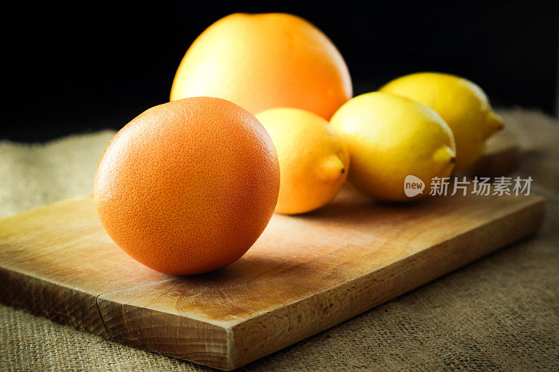 柚子和柠檬放在木砧板上，深色背景